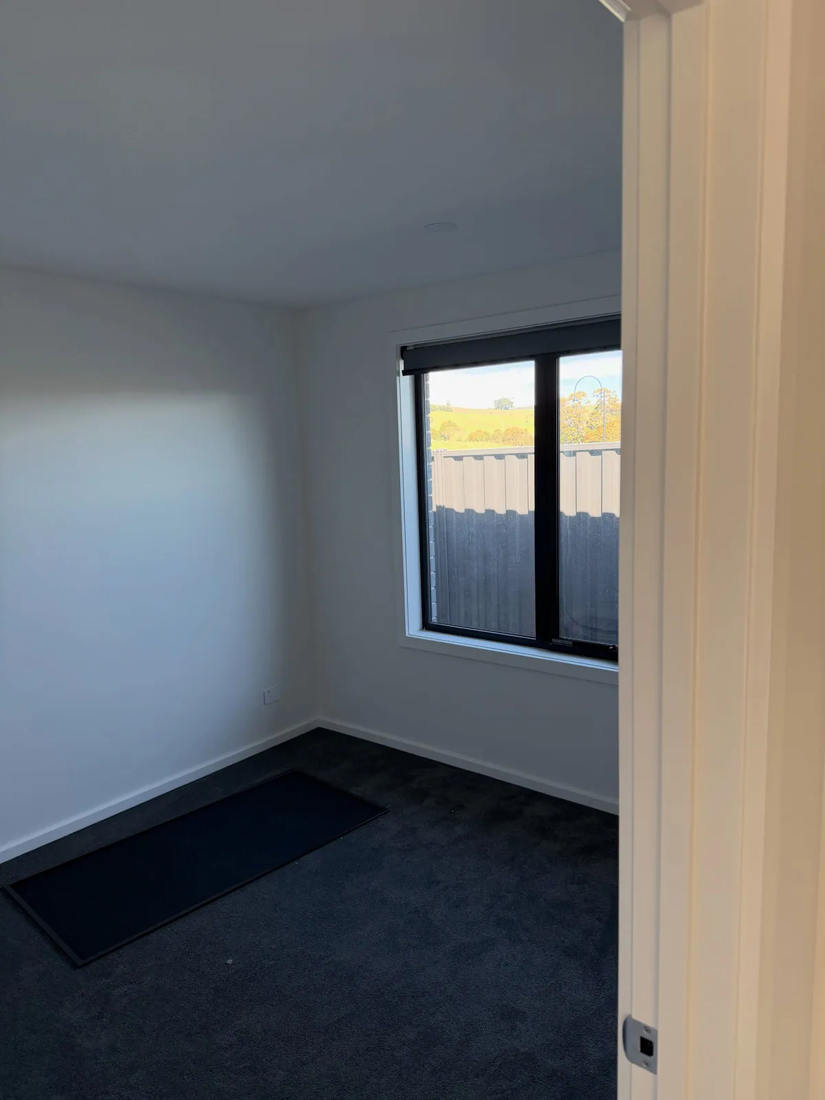 White bedroom in a new build with a black-framed window