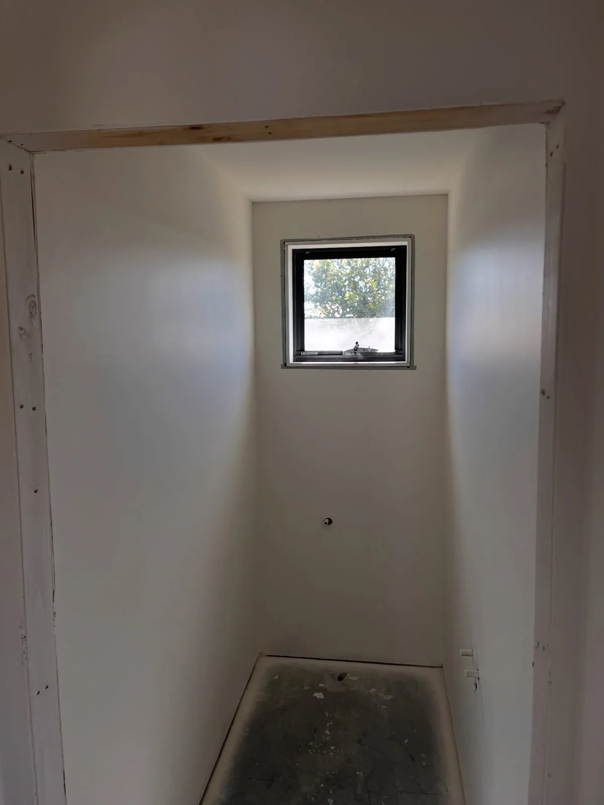 Narrow alcove with a small window, walls sprayed out in white