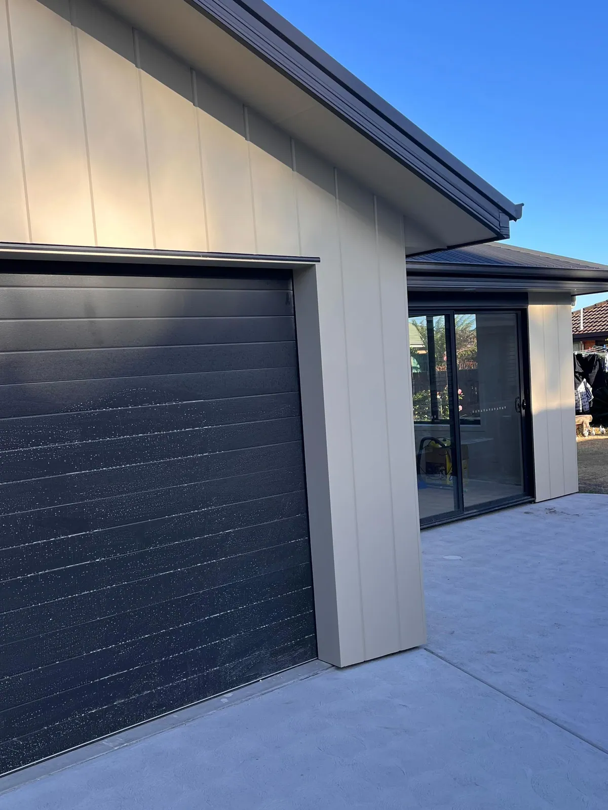 Garage with pale vertical cladding and a dark roller door