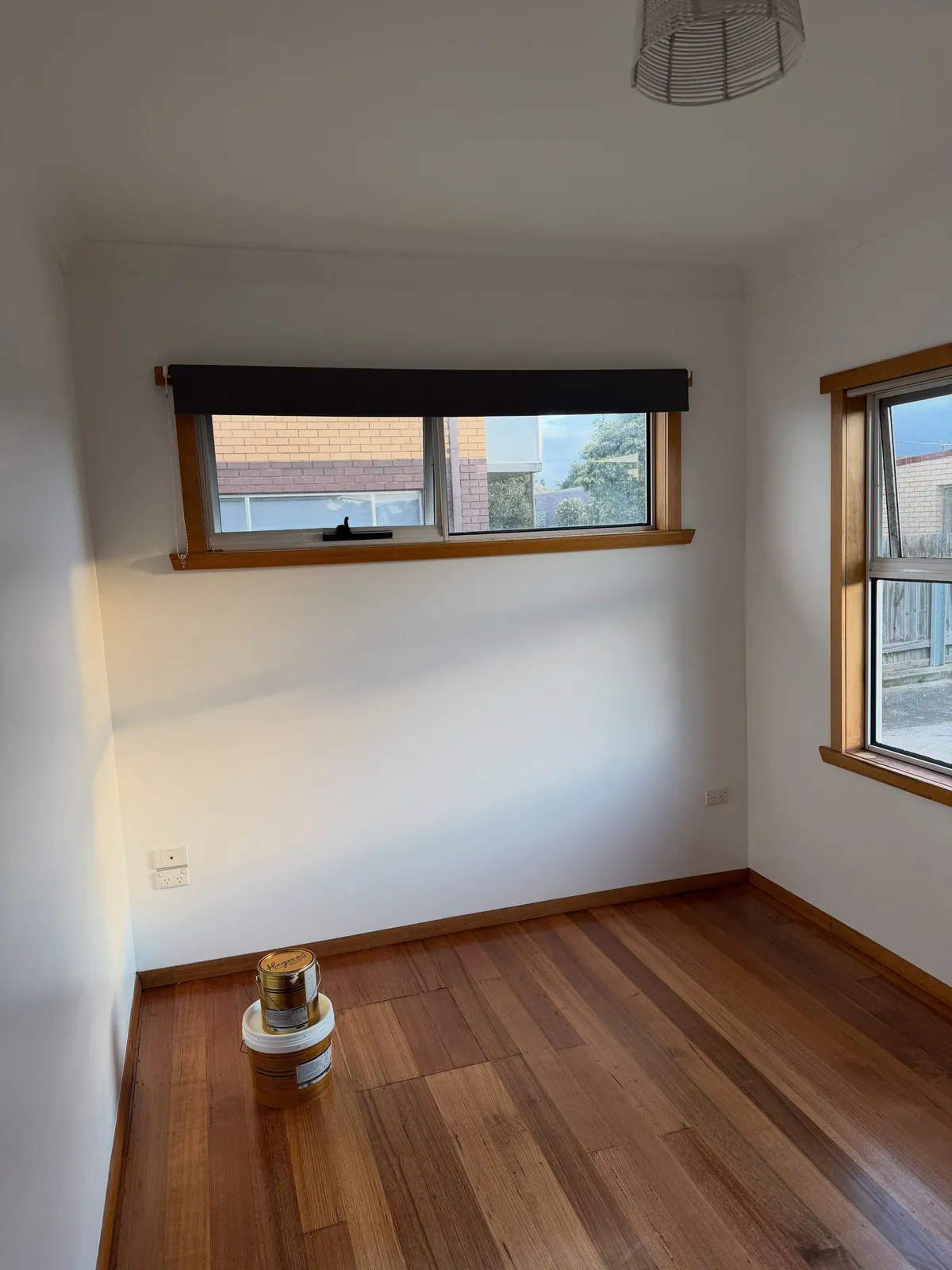 The same bedroom after: white walls, timber window and floorboards